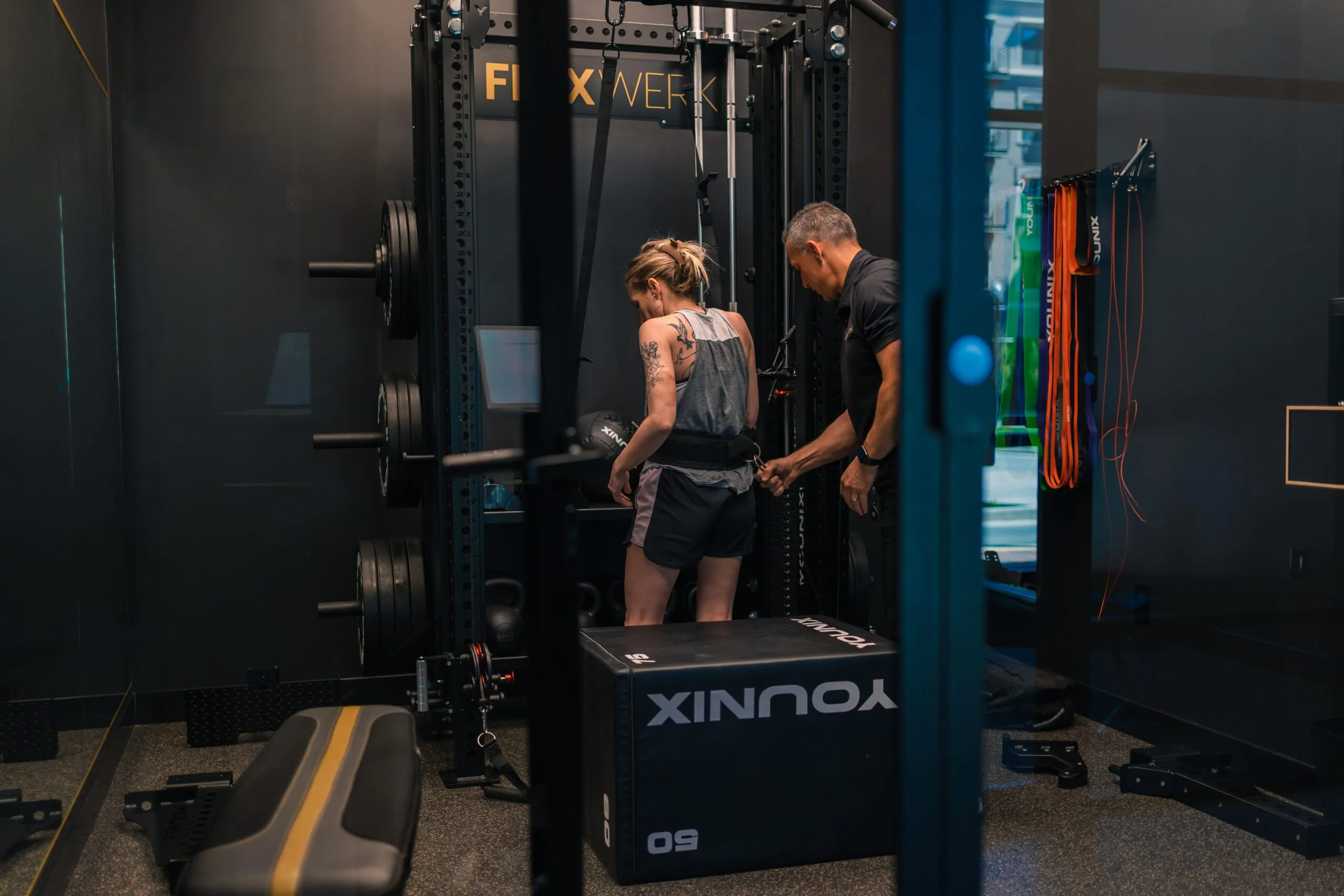 A coach guiding a client through a cable exercise inside a FlexSpace Plus space